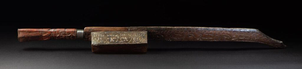 This great sword from the Paiwan tribe is decorated with embossed brass engraved with faces on the front and the side while the back is carved with three characters in the pure Paiwan style.