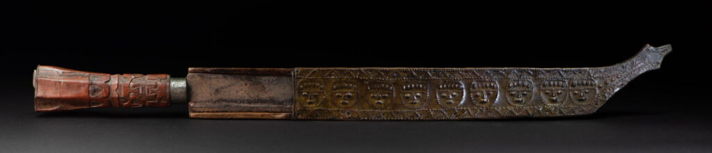This great sword from the Paiwan tribe is decorated with embossed brass engraved with faces on the front and the side while the back is carved with three characters in the pure Paiwan style.