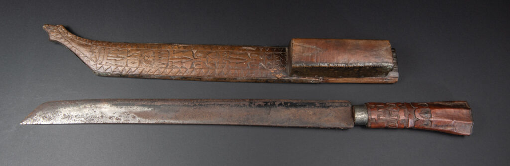 This great sword from the Paiwan tribe is decorated with embossed brass engraved with faces on the front and the side while the back is carved with three characters in the pure Paiwan style.