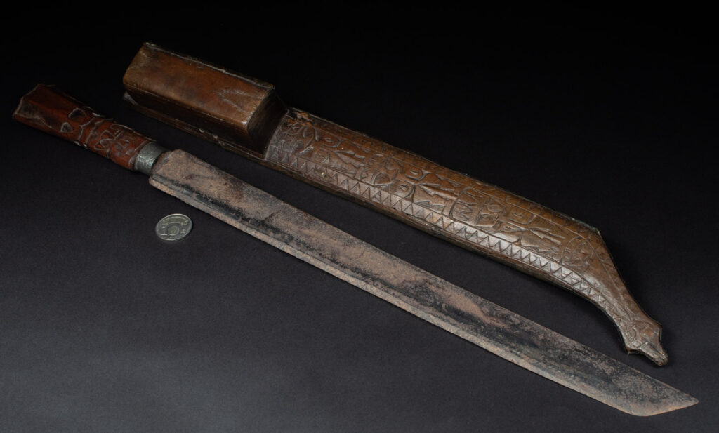 This great sword from the Paiwan tribe is decorated with embossed brass engraved with faces on the front and the side while the back is carved with three characters in the pure Paiwan style.