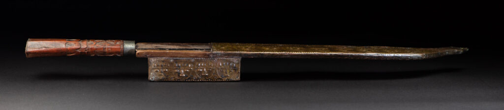 This great sword from the Paiwan tribe is decorated with embossed brass engraved with faces on the front and the side while the back is carved with three characters in the pure Paiwan style.