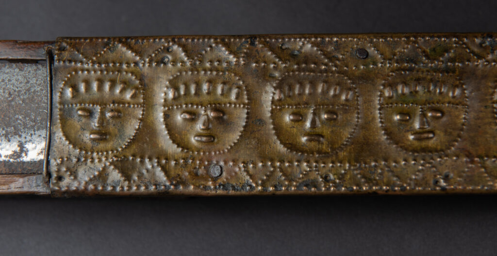 This great sword from the Paiwan tribe is decorated with embossed brass engraved with faces on the front and the side while the back is carved with three characters in the pure Paiwan style.