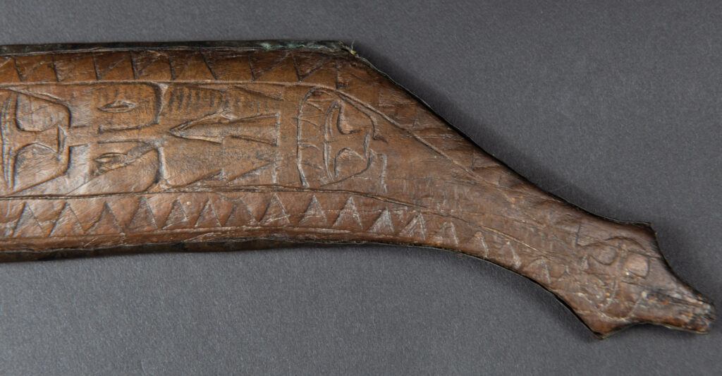 This great sword from the Paiwan tribe is decorated with embossed brass engraved with faces on the front and the side while the back is carved with three characters in the pure Paiwan style.
