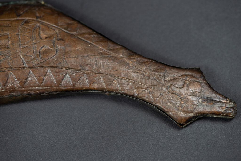 This great sword from the Paiwan tribe is decorated with embossed brass engraved with faces on the front and the side while the back is carved with three characters in the pure Paiwan style.