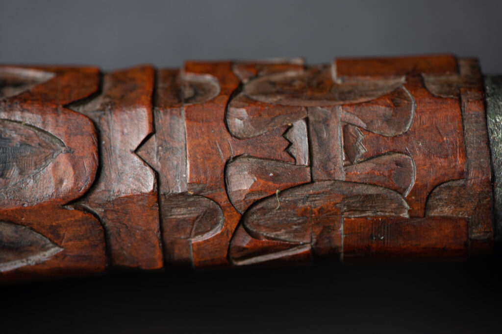 This great sword from the Paiwan tribe is decorated with embossed brass engraved with faces on the front and the side while the back is carved with three characters in the pure Paiwan style.