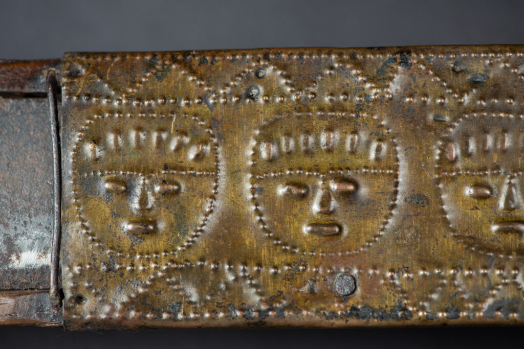 This great sword from the Paiwan tribe is decorated with embossed brass engraved with faces on the front and the side while the back is carved with three characters in the pure Paiwan style.