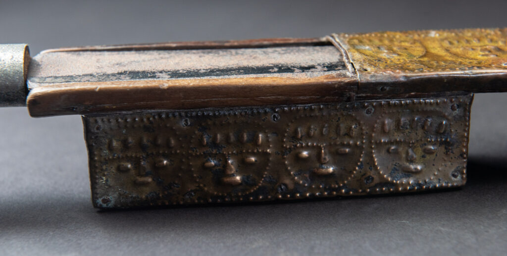 This great sword from the Paiwan tribe is decorated with embossed brass engraved with faces on the front and the side while the back is carved with three characters in the pure Paiwan style.