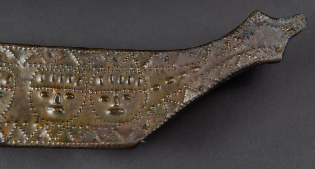 This great sword from the Paiwan tribe is decorated with embossed brass engraved with faces on the front and the side while the back is carved with three characters in the pure Paiwan style.