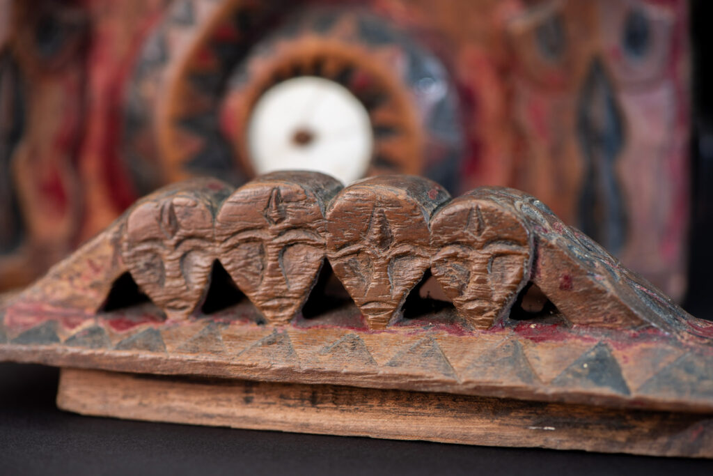 Paiwan tribe Shaman box with a sliding lid topped with carved faces, painted with red pigments, featuring full-length figures and the sacred snake, and decorated with mother-of-pearl.