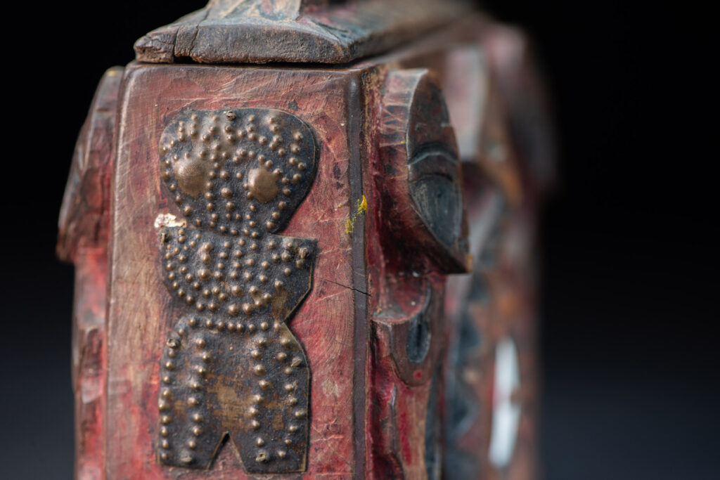 Paiwan tribe Shaman box with a sliding lid topped with carved faces, painted with red pigments, featuring full-length figures and the sacred snake, and decorated with mother-of-pearl.