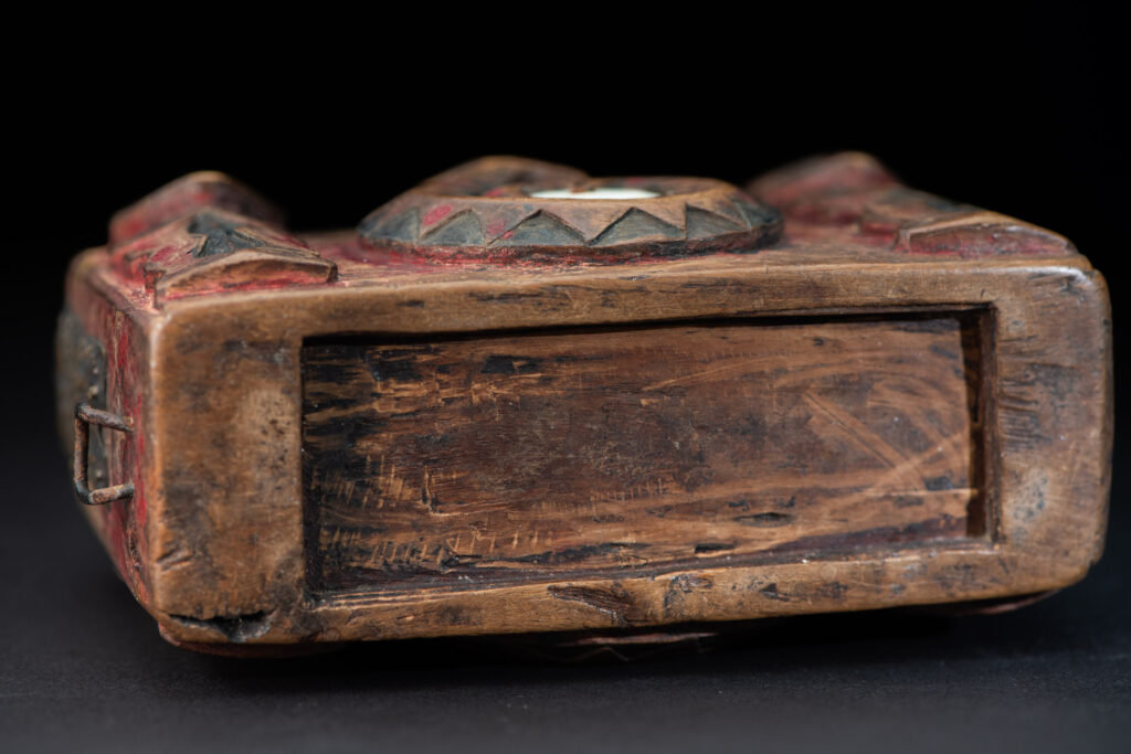 Paiwan tribe Shaman box with a sliding lid topped with carved faces, painted with red pigments, featuring full-length figures and the sacred snake, and decorated with mother-of-pearl.
