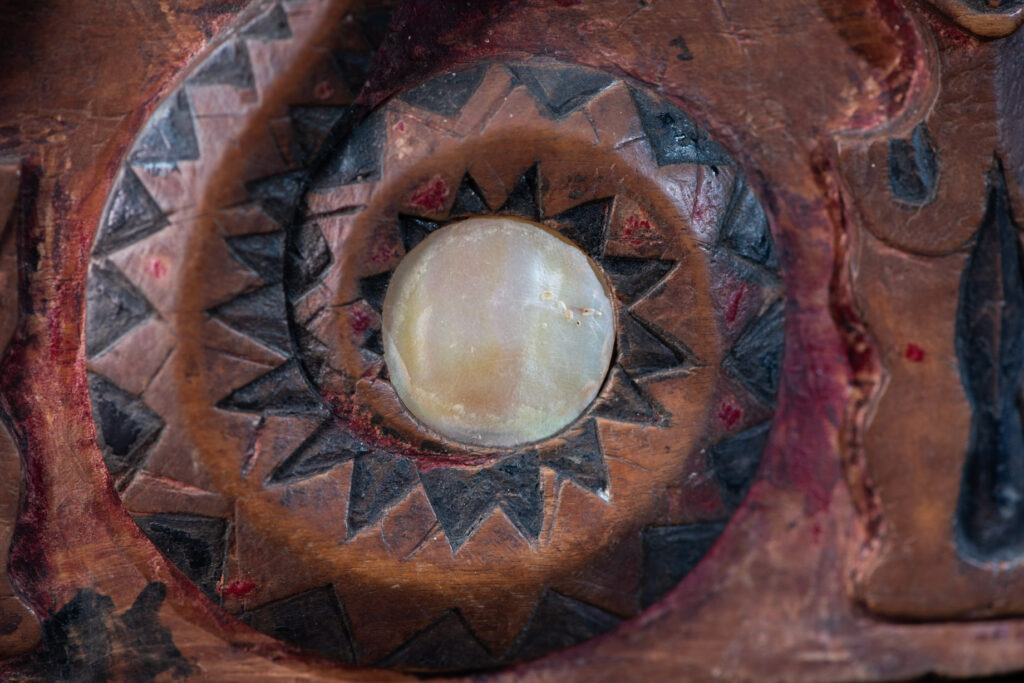 Paiwan tribe Shaman box with a sliding lid topped with carved faces, painted with red pigments, featuring full-length figures and the sacred snake, and decorated with mother-of-pearl.