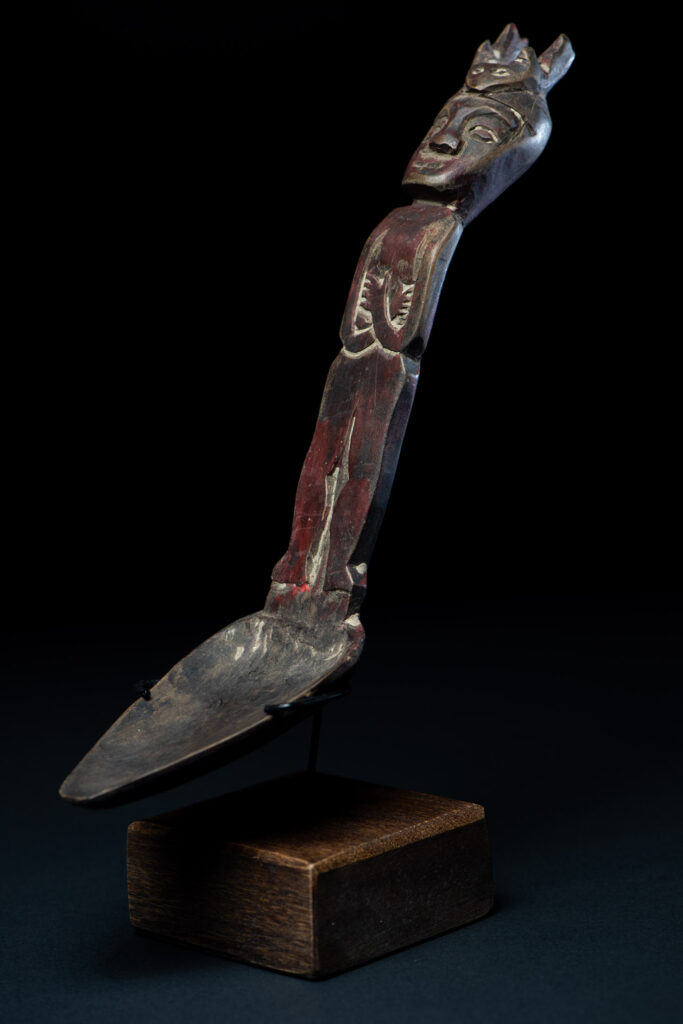 Old spoon from the Paiwan tribe, tinted with red pigments and depicting an ancestor wearing a ceremonial headdress.