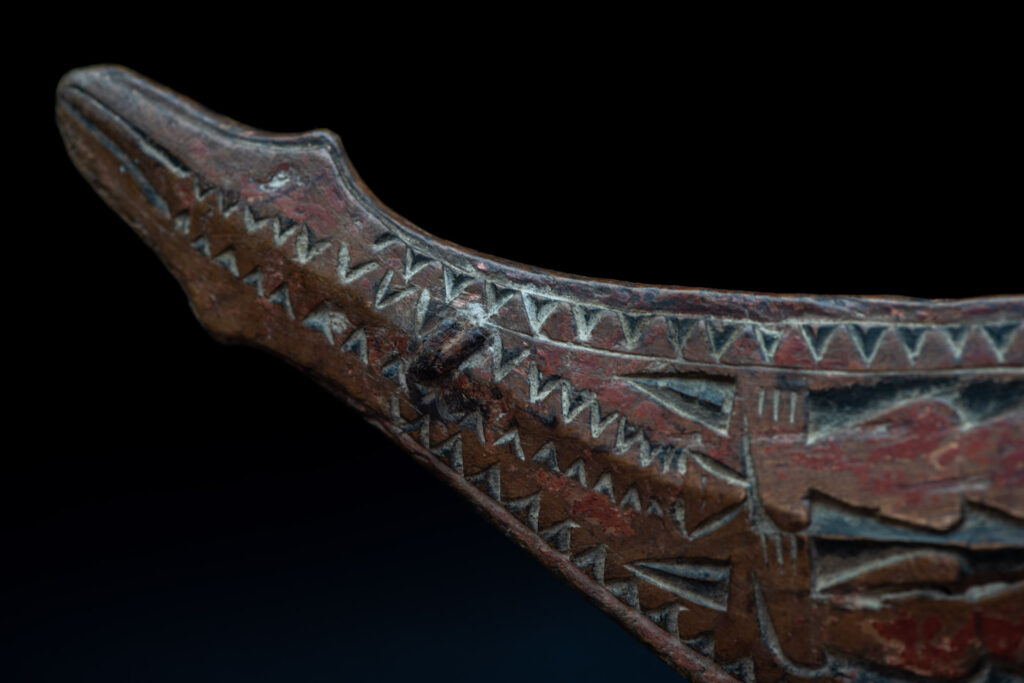 Paiwan tribe hunting knife with a sheath carved with a standing figure and human faces on the side. The hilt is made of carved wood.