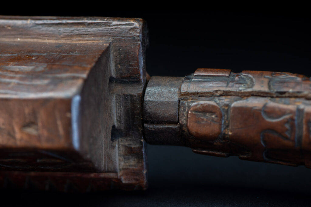 Paiwan tribe hunting knife with a sheath carved with a standing figure and human faces on the side. The hilt is made of carved wood.