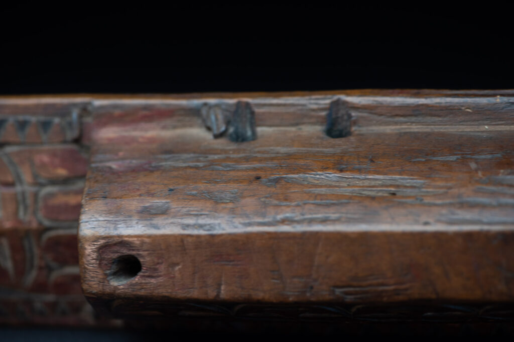 Paiwan tribe hunting knife with a sheath carved with a standing figure and human faces on the side. The hilt is made of carved wood.