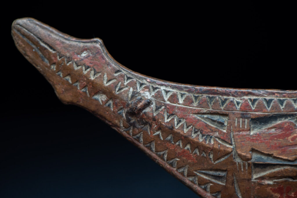 Paiwan tribe hunting knife with a sheath carved with a standing figure and human faces on the side. The hilt is made of carved wood.