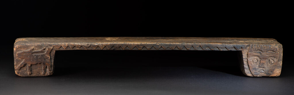 Paiwan tribe headrest in wood carved with human head pattern and deer on both side which represent abundant harvest and performance of ability.