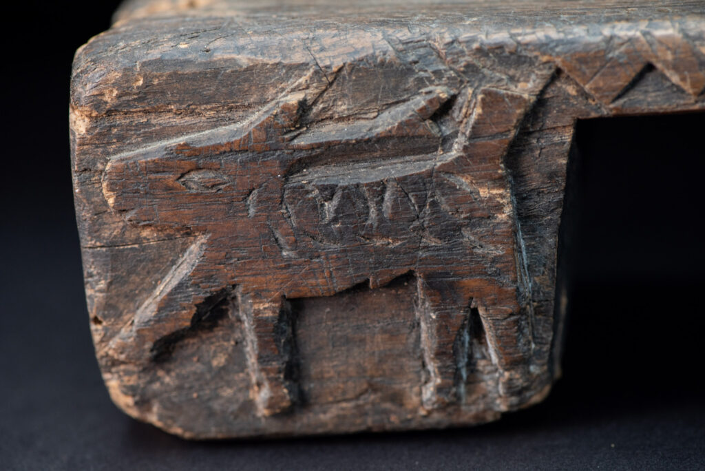 Paiwan tribe headrest in wood carved with human head pattern and deer on both side which represent abundant harvest and performance of ability.