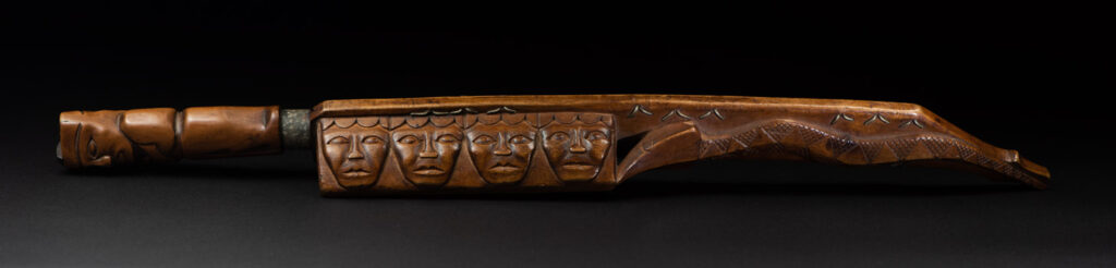 Very fine sword from the Paiwan tribe, carved with the sacred snake and human faces along the sides. The hilt features a full-length standing figure.