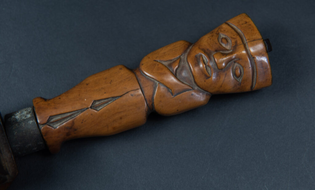Very fine sword from the Paiwan tribe, carved with the sacred snake and human faces along the sides. The hilt features a full-length standing figure.