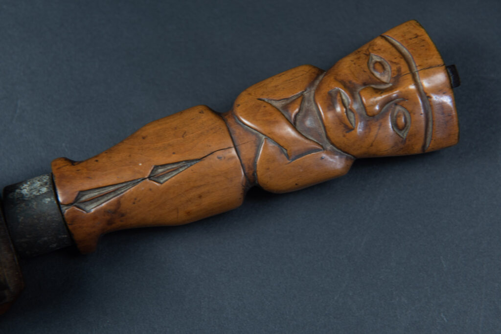Very fine sword from the Paiwan tribe, carved with the sacred snake and human faces along the sides. The hilt features a full-length standing figure.