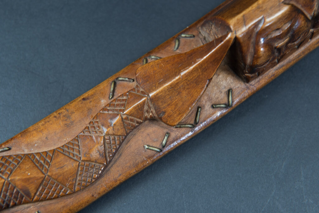 Very fine sword from the Paiwan tribe, carved with the sacred snake and human faces along the sides. The hilt features a full-length standing figure.