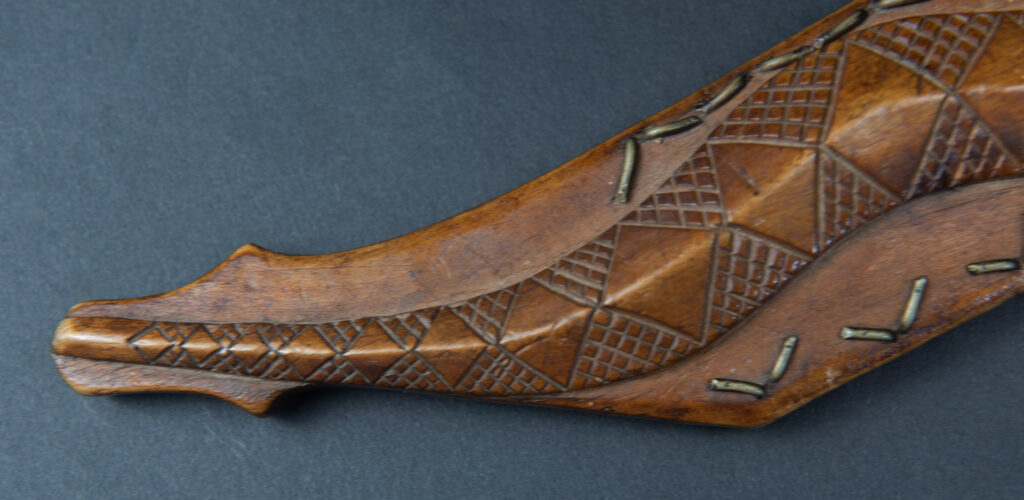 Very fine sword from the Paiwan tribe, carved with the sacred snake and human faces along the sides. The hilt features a full-length standing figure.