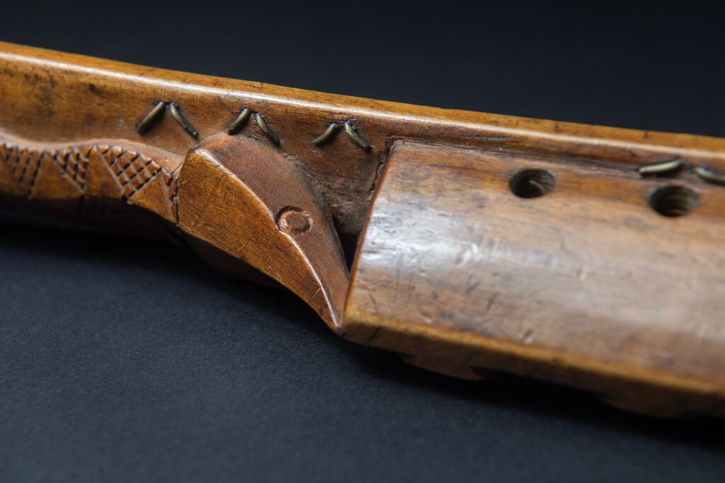 Very fine sword from the Paiwan tribe, carved with the sacred snake and human faces along the sides. The hilt features a full-length standing figure.