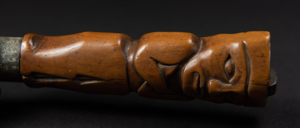 Very fine sword from the Paiwan tribe, carved with the sacred snake and human faces along the sides. The hilt features a full-length standing figure.