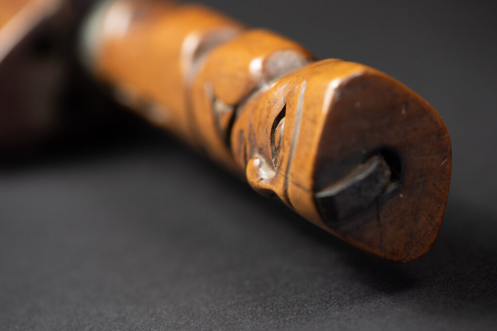 Very fine sword from the Paiwan tribe, carved with the sacred snake and human faces along the sides. The hilt features a full-length standing figure.