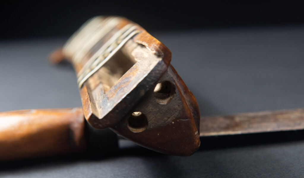 Very fine sword from the Paiwan tribe, carved with the sacred snake and human faces along the sides. The hilt features a full-length standing figure.