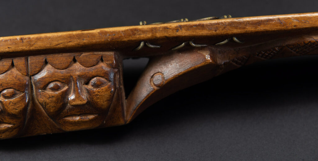 Very fine sword from the Paiwan tribe, carved with the sacred snake and human faces along the sides. The hilt features a full-length standing figure.