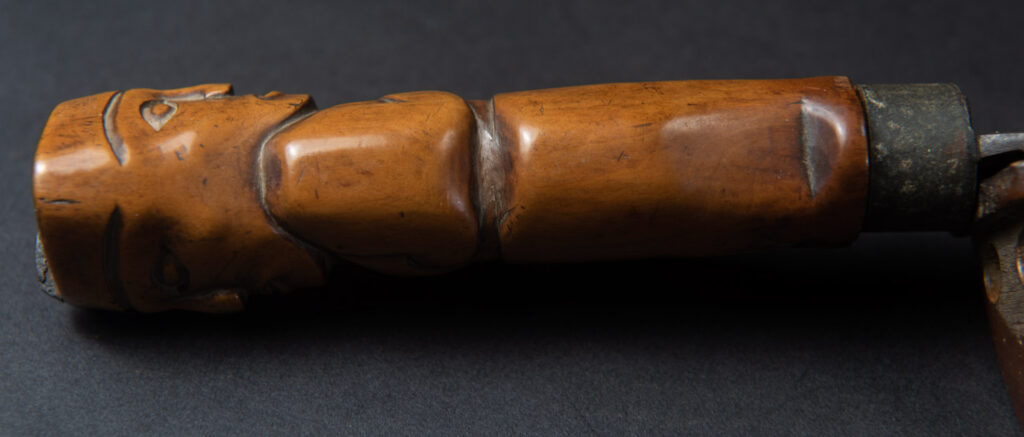 Very fine sword from the Paiwan tribe, carved with the sacred snake and human faces along the sides. The hilt features a full-length standing figure.