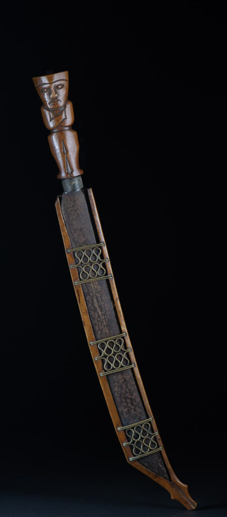 Very fine sword from the Paiwan tribe, carved with the sacred snake and human faces along the sides. The hilt features a full-length standing figure.