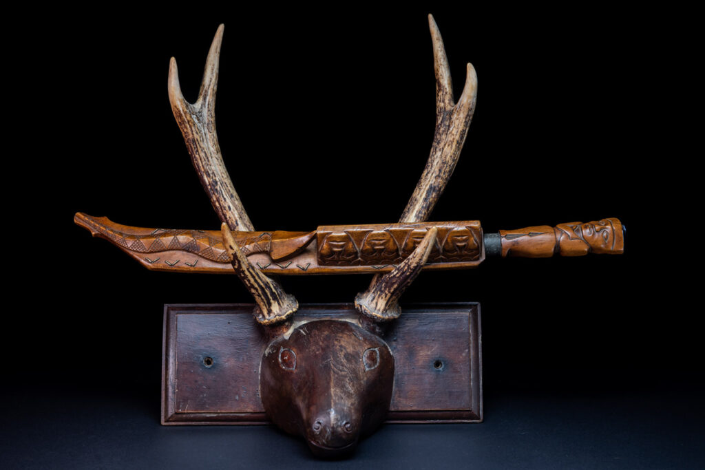 Very fine sword from the Paiwan tribe, carved with the sacred snake and human faces along the sides. The hilt features a full-length standing figure.