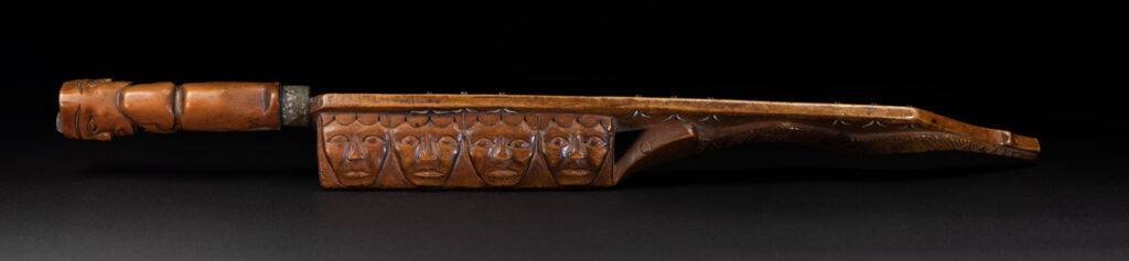 Very fine sword from the Paiwan tribe, carved with the sacred snake and human faces along the sides. The hilt features a full-length standing figure.