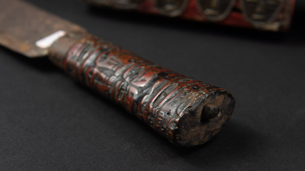 Paiwan tribe ancient sword painted in red, carved with standing figures and humain faces on the side.