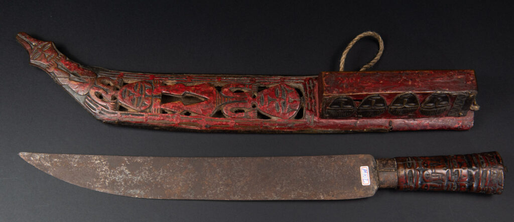 Paiwan tribe ancient sword painted in red, carved with standing figures and humain faces on the side.