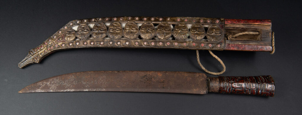 Paiwan tribe ancient sword painted in red, carved with standing figures and humain faces on the side.