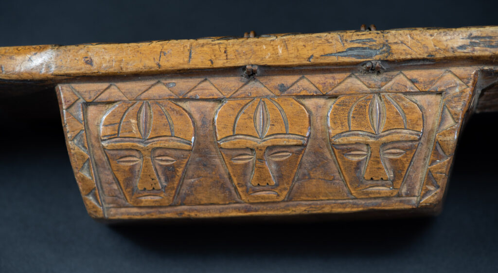 Short sword from the Paiwan tribe, with a sheath carved with a standing figure. The side of the sheath is adorned with three sculpted human heads. The sword is made in one piece with the handle, which is wrapped in rattan.