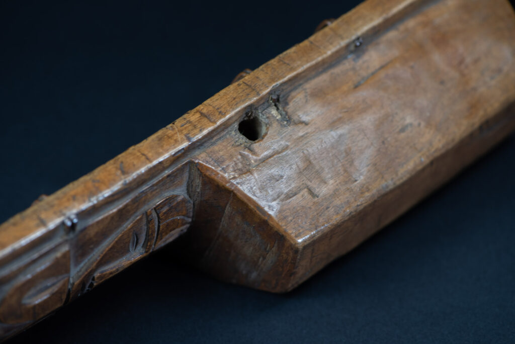 Short sword from the Paiwan tribe, with a sheath carved with a standing figure. The side of the sheath is adorned with three sculpted human heads. The sword is made in one piece with the handle, which is wrapped in rattan.