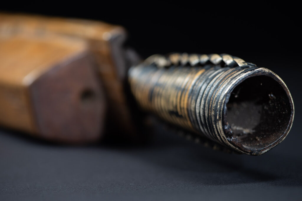 Short sword from the Paiwan tribe, with a sheath carved with a standing figure. The side of the sheath is adorned with three sculpted human heads. The sword is made in one piece with the handle, which is wrapped in rattan.