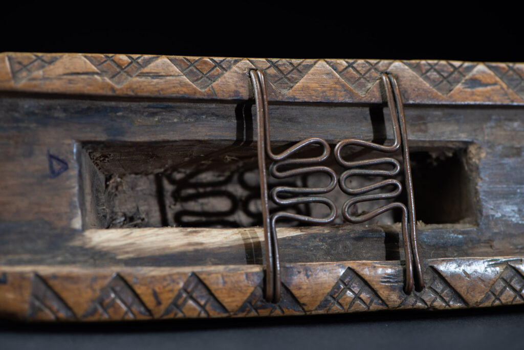 Short sword from the Paiwan tribe, with a sheath carved with a standing figure. The side of the sheath is adorned with three sculpted human heads. The sword is made in one piece with the handle, which is wrapped in rattan.