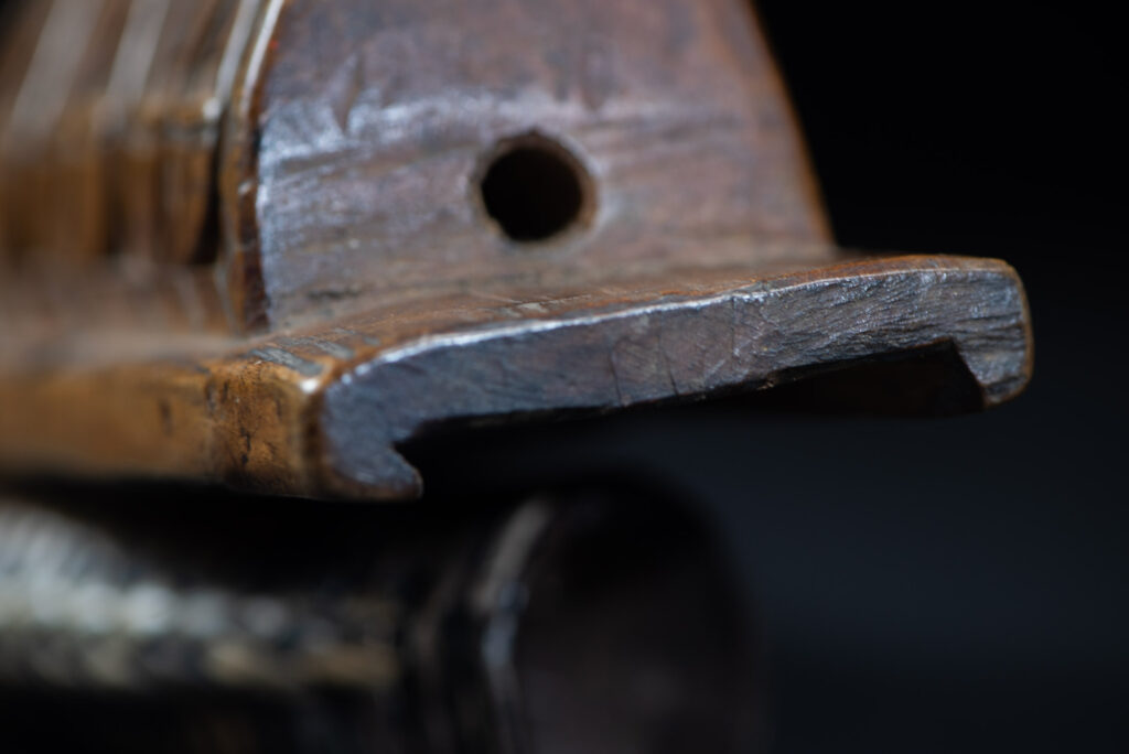 Short sword from the Paiwan tribe, with a sheath carved with a standing figure. The side of the sheath is adorned with three sculpted human heads. The sword is made in one piece with the handle, which is wrapped in rattan.