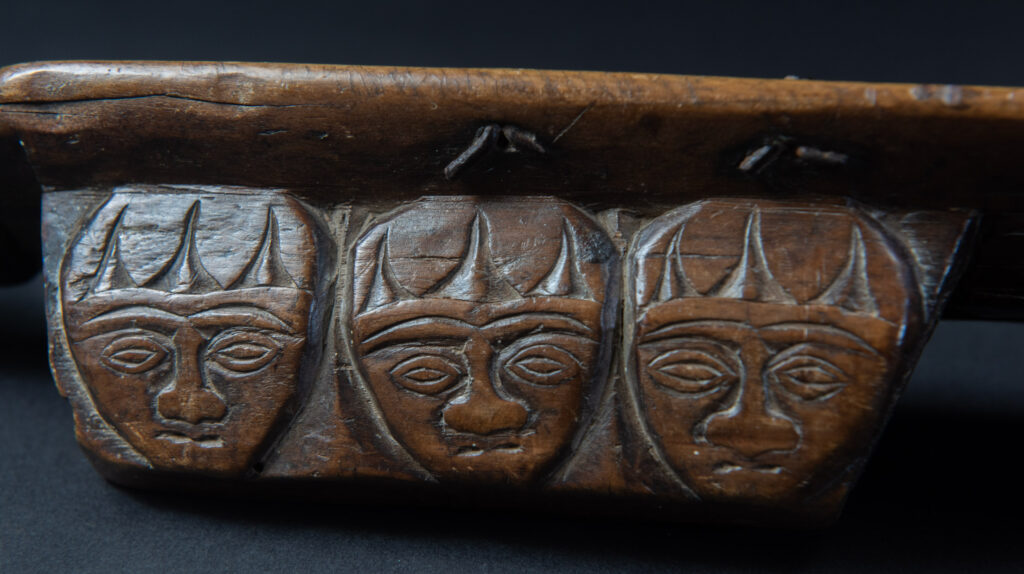 Paiwan tribe hunting knife with a sheath carved with a standing figure and human faces on the side. The hilt is made of carved wood.