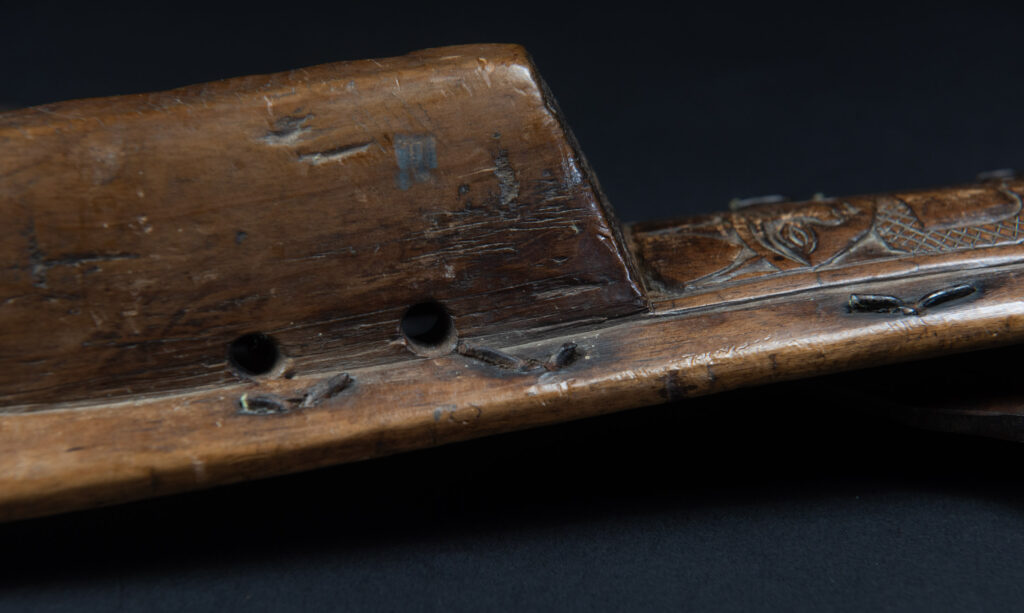 Paiwan tribe hunting knife with a sheath carved with a standing figure and human faces on the side. The hilt is made of carved wood.