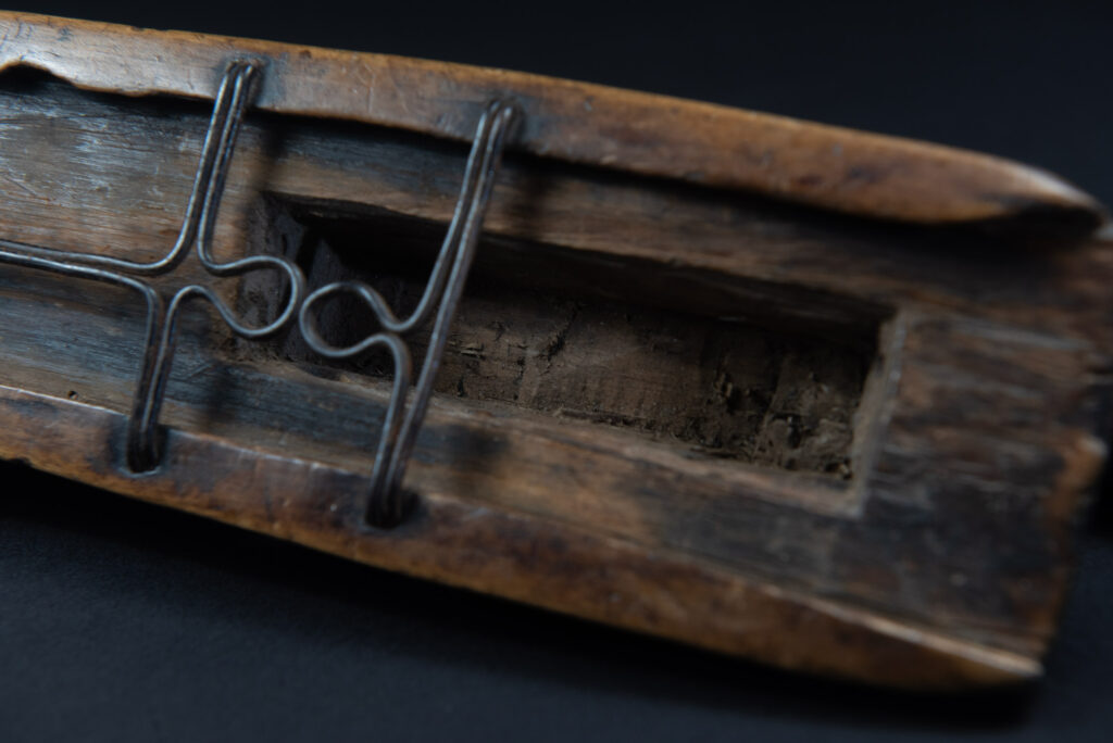 Paiwan tribe hunting knife with a sheath carved with a standing figure and human faces on the side. The hilt is made of carved wood.