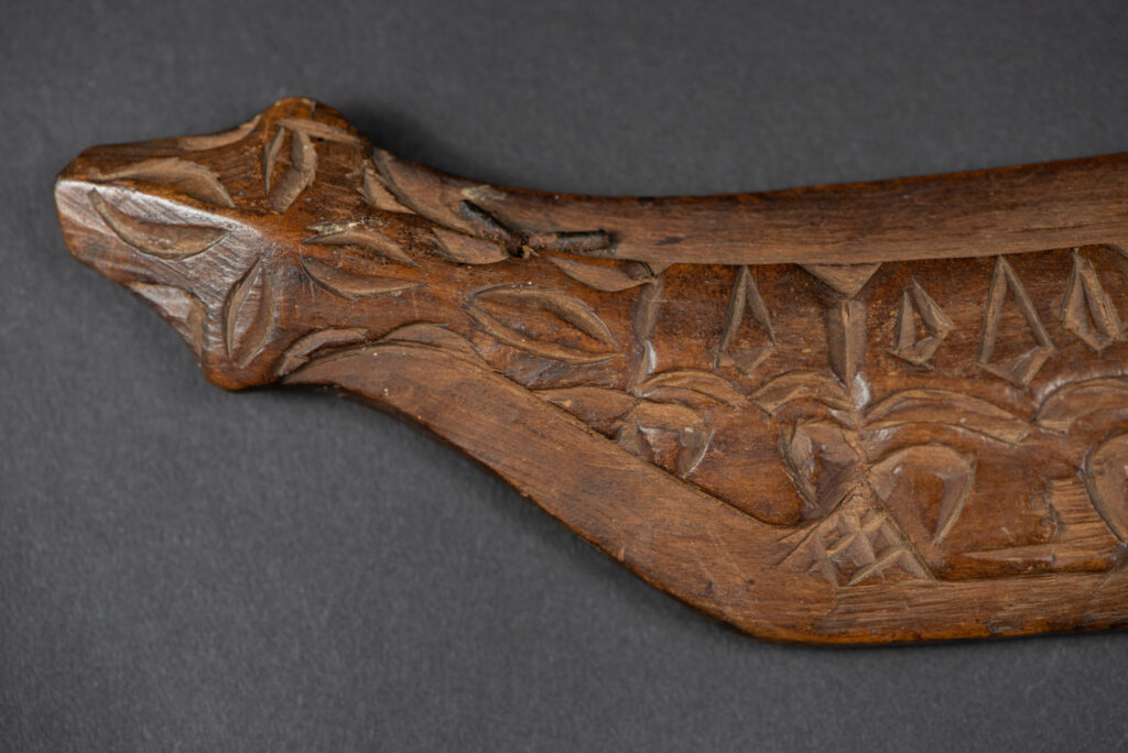 Very fine old sword from the Paiwan tribe, with a scabbard carved with multiple human faces. One side is inlaid with three faience circles.