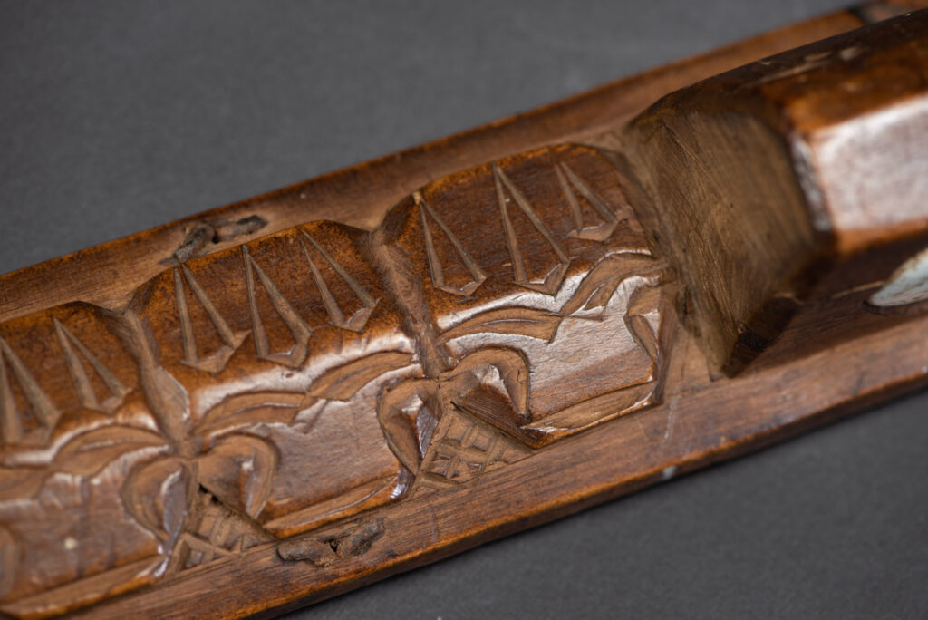 Very fine old sword from the Paiwan tribe, with a scabbard carved with multiple human faces. One side is inlaid with three faience circles.